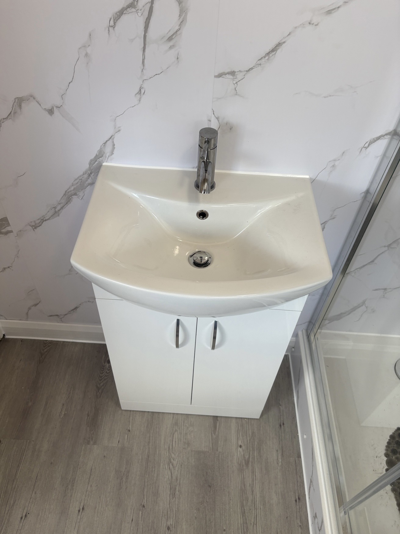 New vanity basin and storage unit beside the completed shower enclosure
