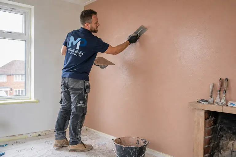 An MP Preservation plasterer skimming a wall with a trowel in a cleared room