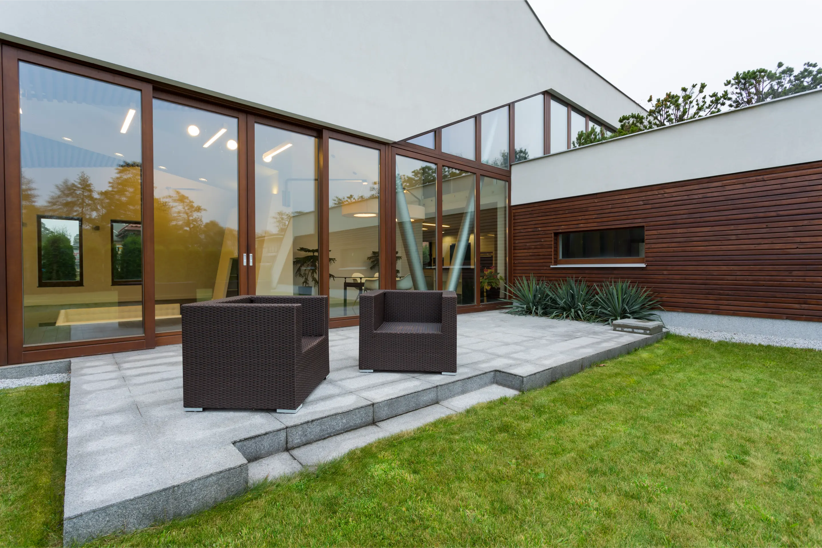 The outside of a completed single storey extension with large glazed doors and a patio