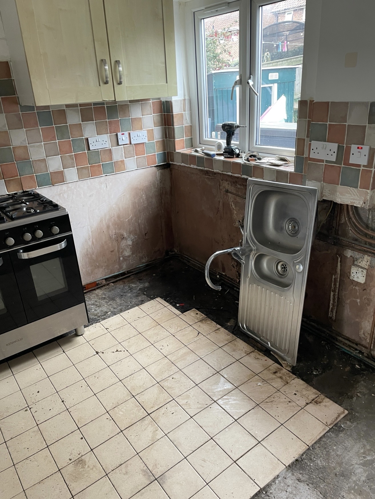 Kitchen units removed to expose damp-damaged wall surfaces behind them