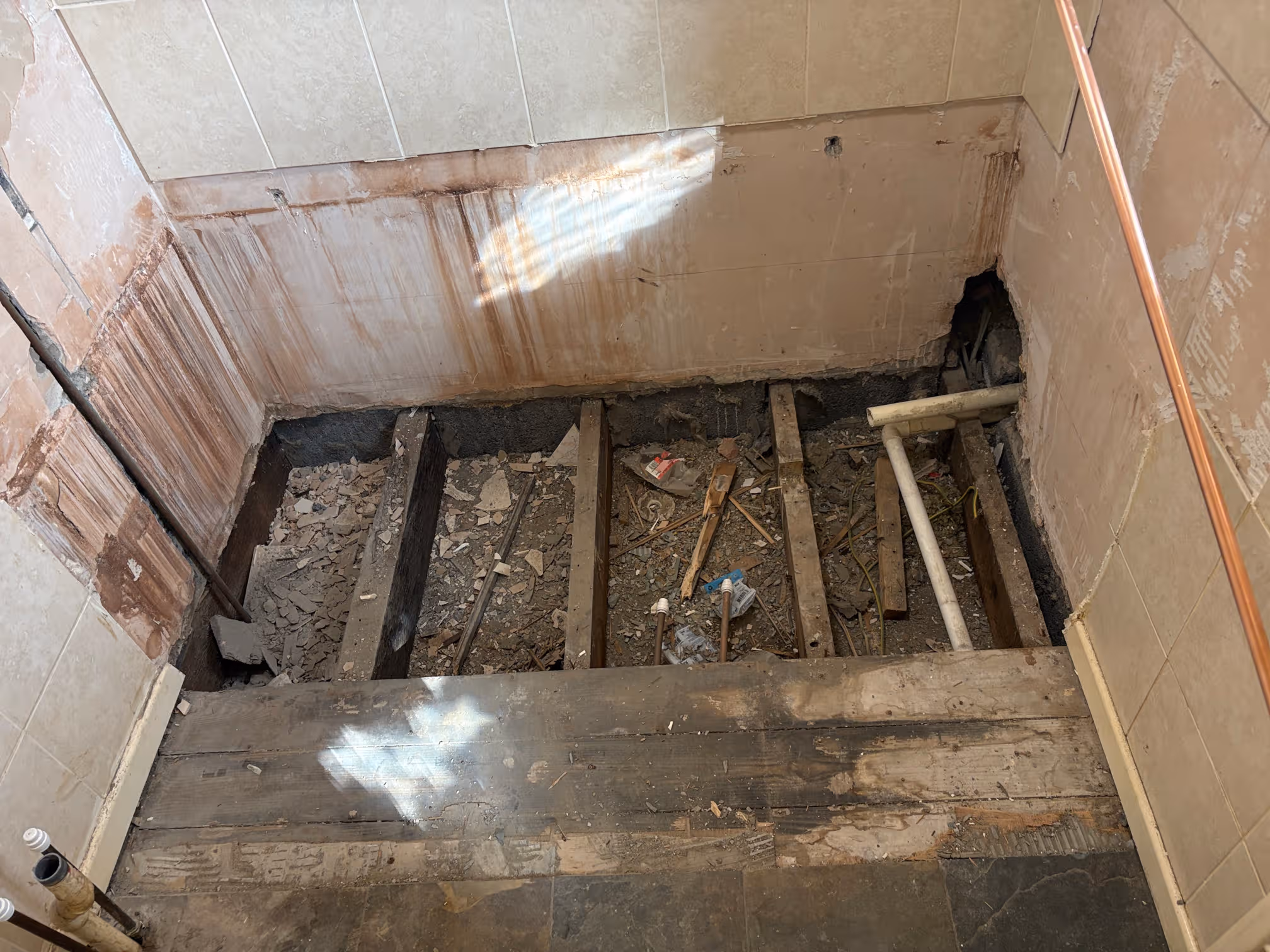 Exposed bathroom floor and wall surfaces during the early refurbishment work