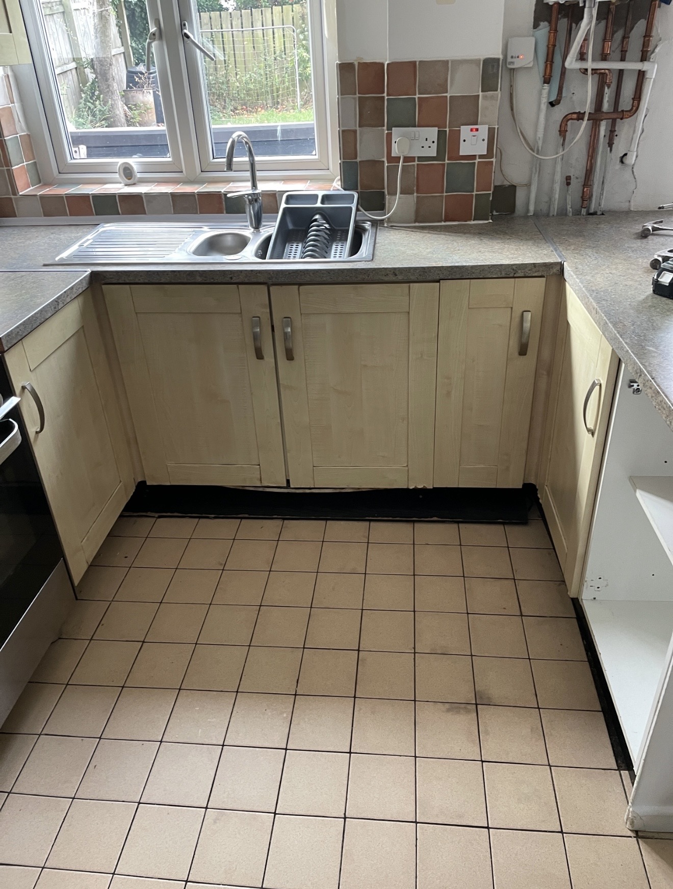 The dated kitchen before refurbishment, with old cabinets, tiles and flooring
